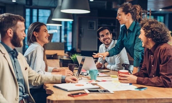 Gruppo di lavoro riunito attorno a un tavolo in un ufficio open space